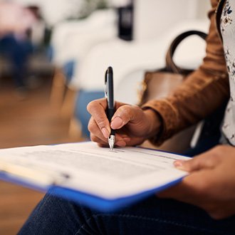 Woman filling out dental insurance form in lobby