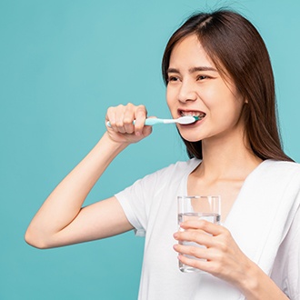 a patient with braces brushing their teeth