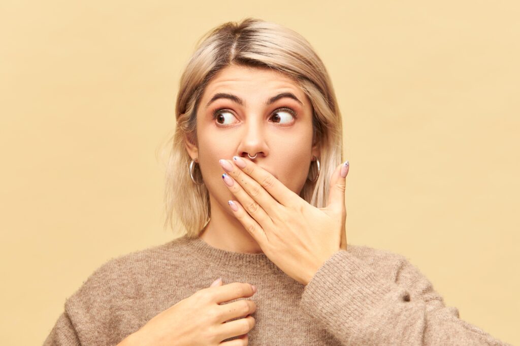 Woman covering her mouth to hide yellow aligners